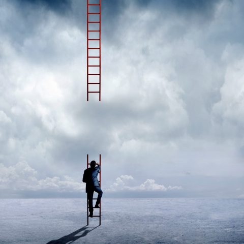 A businessman attempts to climb a large red ladder that has a big missing segment that will prevent him from reaching his destination.